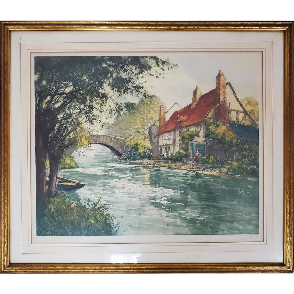 Framed color etching or print of a riverside village with a stone bridge, leafy tree on the left, and red-roofed buildings in the distance.