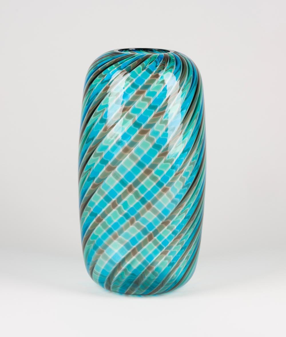 Blue and teal glass vase with wavy vertical striations and a patterned swirl body on a white background.