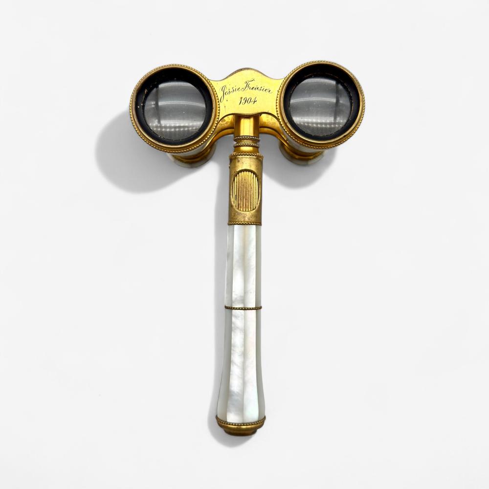 Pair of gold-framed opera glasses with round lenses and a mother-of-pearl handle, shown against a light background.