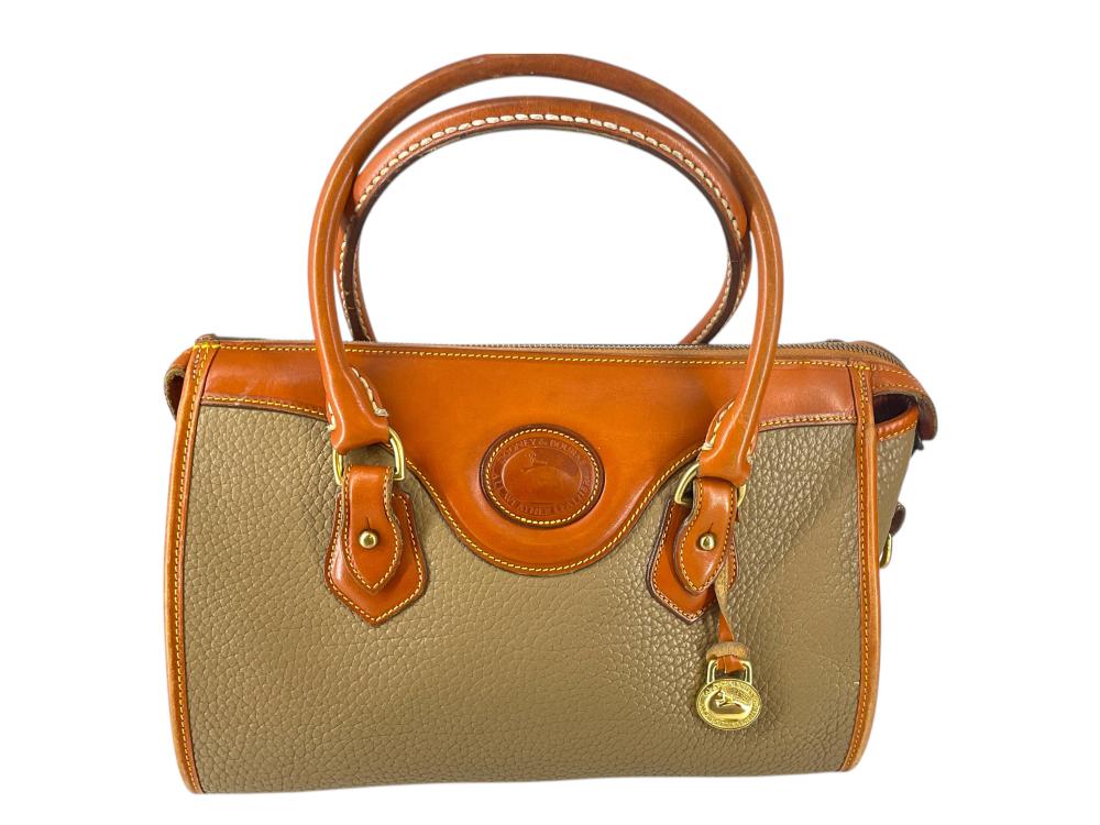 Vintage two-tone leather satchel purse with tan top handle, orange trim, flap with circular logo, and side buckles.