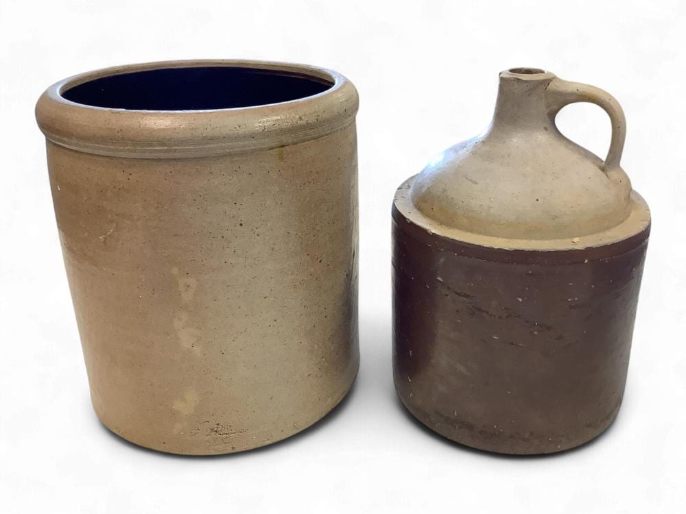 Two stoneware crocks and jug forms on a white background: a tall cylindrical crock and a smaller handled jug with dark brown glaze around the midsection.