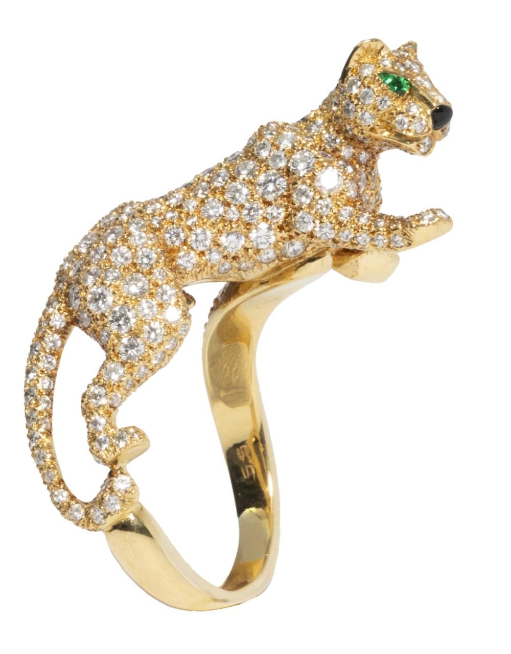 Gold panther-shaped diamond ring with a green gem on the head, shown on a white background.