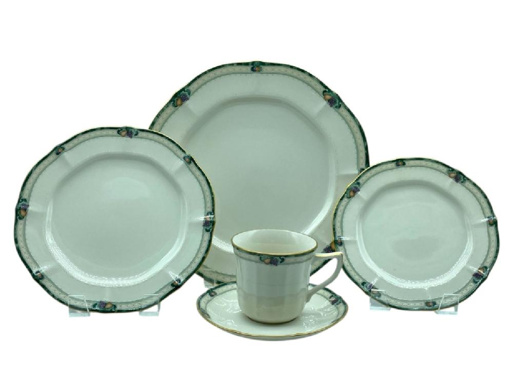 Three white china plates and a teacup on saucer with green and gold trim, shown against a white background.
