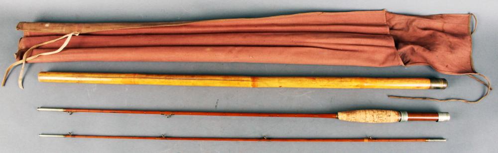 Four-piece fly fishing rod laid horizontally with an orange-brown canvas sleeve and visible rod tips and reel seat area.