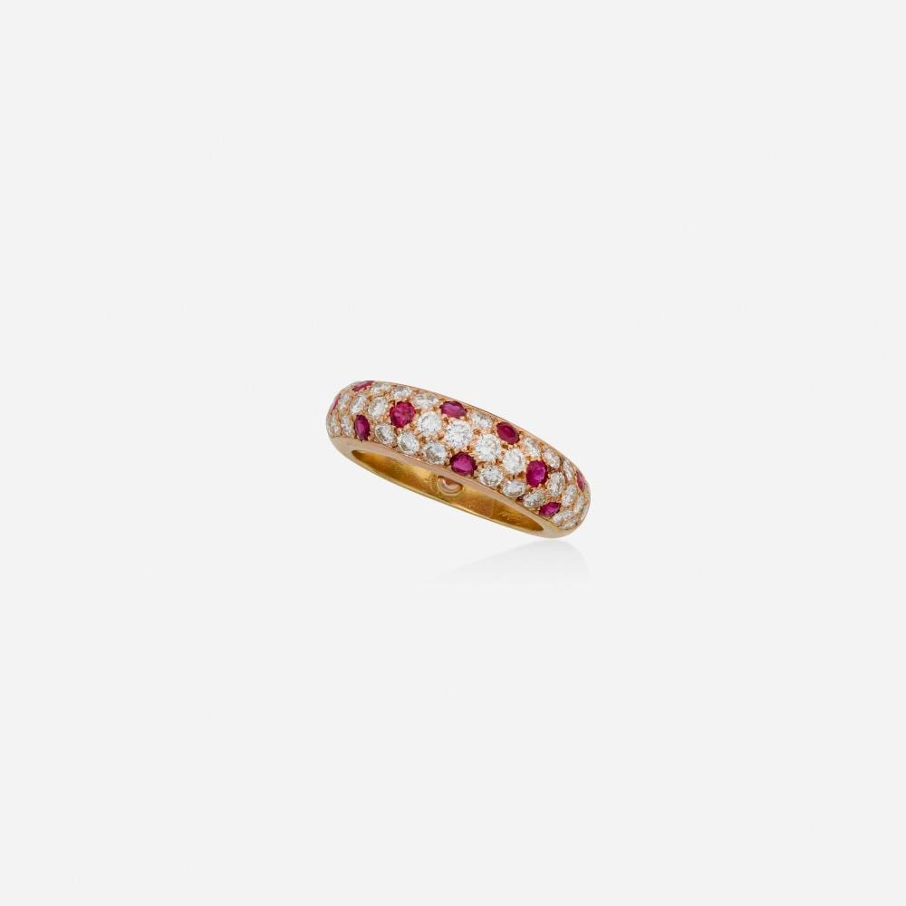 Gold band ring with a row of red gemstones and small clear stones around the top surface.