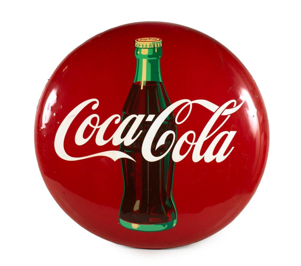 Round red Coca-Cola button sign with a green bottle graphic and white script Coca-Cola lettering.