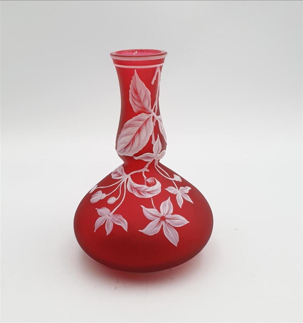 Red glass vase with a rounded body and narrow neck, decorated with white floral/leaf motifs applied in relief.
