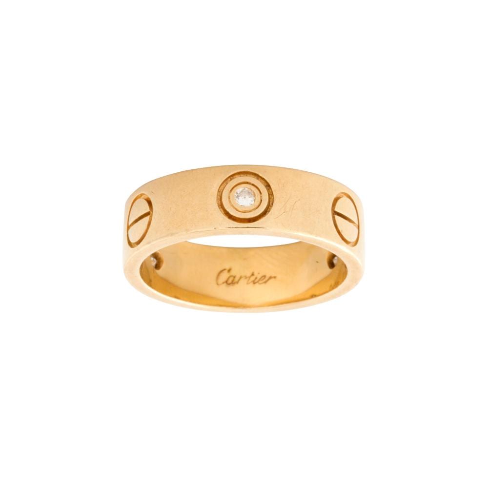 Gold ring with a round diamond set in the center and "Cartier" engraved on the inside band.