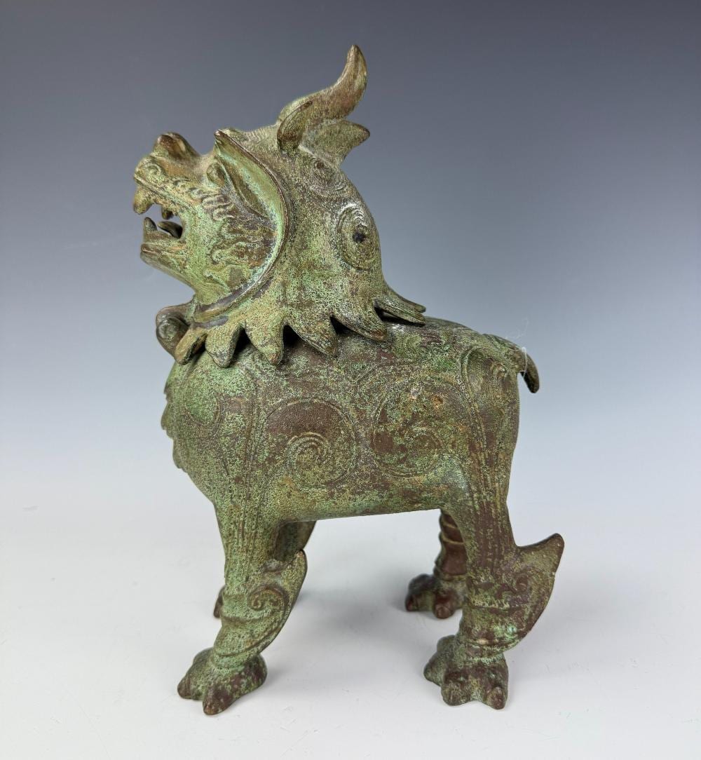 Green bronze foo dog incense burner shaped like a standing mythical guardian with open mouth and curled decorative details.