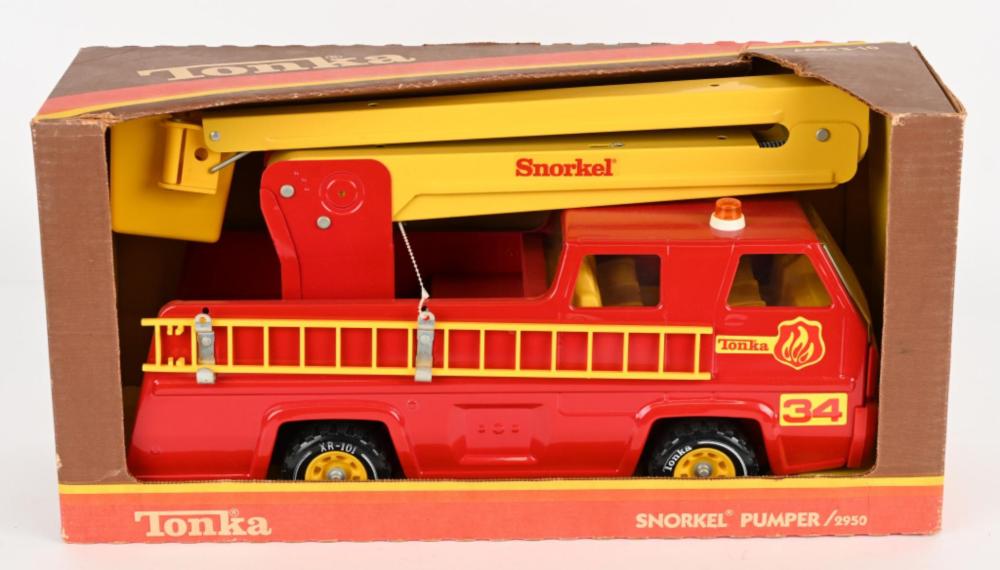 Red and yellow toy press-steel fire truck with “Snorkel” label, shown inside a cardboard box.