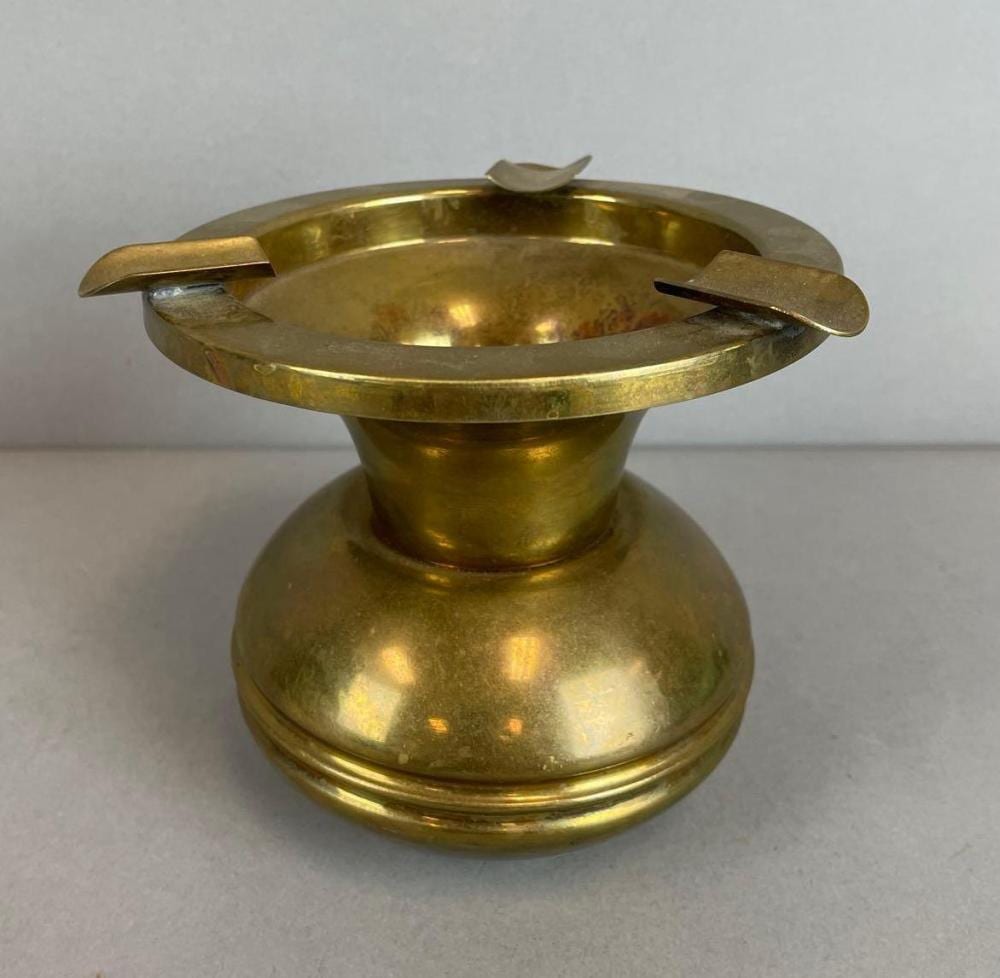 Brass spittoon or ash tray with wide circular rim and two curved handles on a gray background.