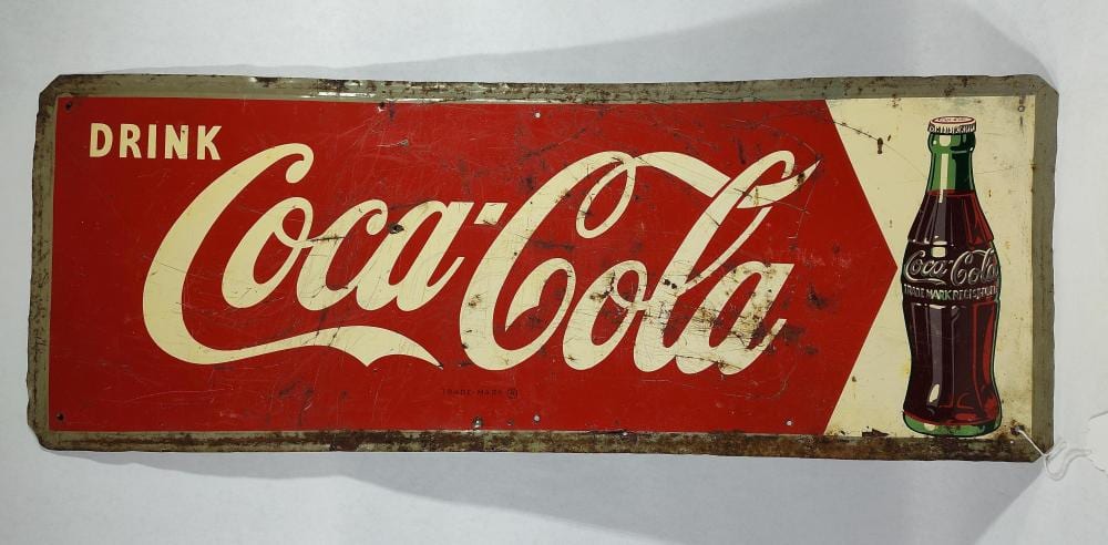 Rectangular vintage red sign with the words “Drink Coca-Cola” in white script and an illustrated Coca-Cola bottle on the right.