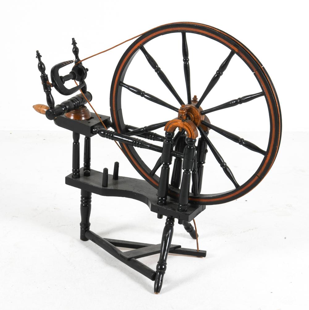 Antique-style wooden spinning wheel with a large round wheel and black stand, photographed on a white background.