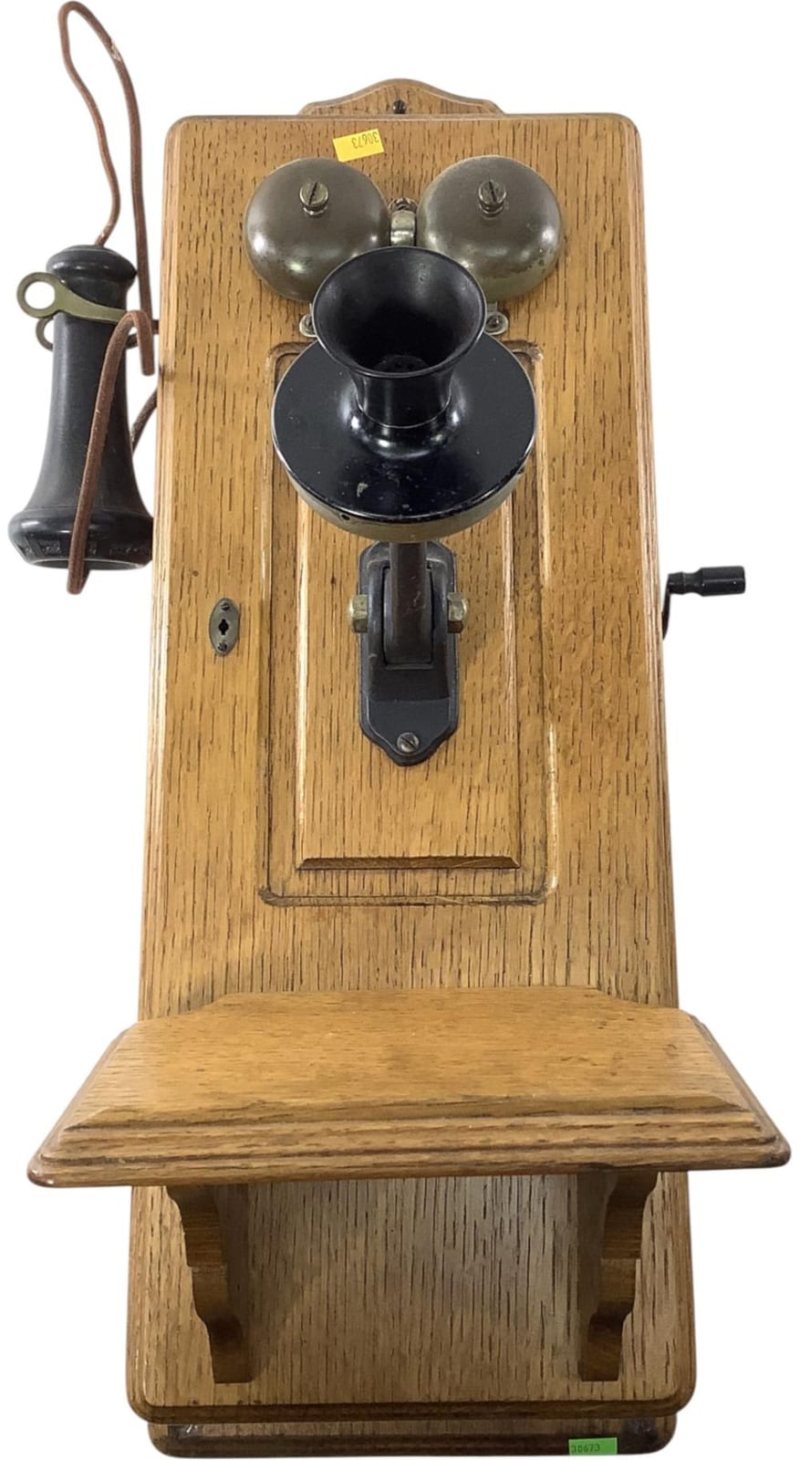 Antique-style wall crank telephone with wooden body, metal bells, and crank handle mounted on a base.