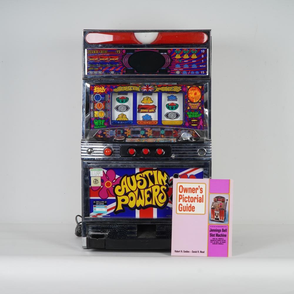 Front view of a vintage video slot machine with colorful game panels and an open instruction booklet titled “Owner’s Pictorial Guide.”