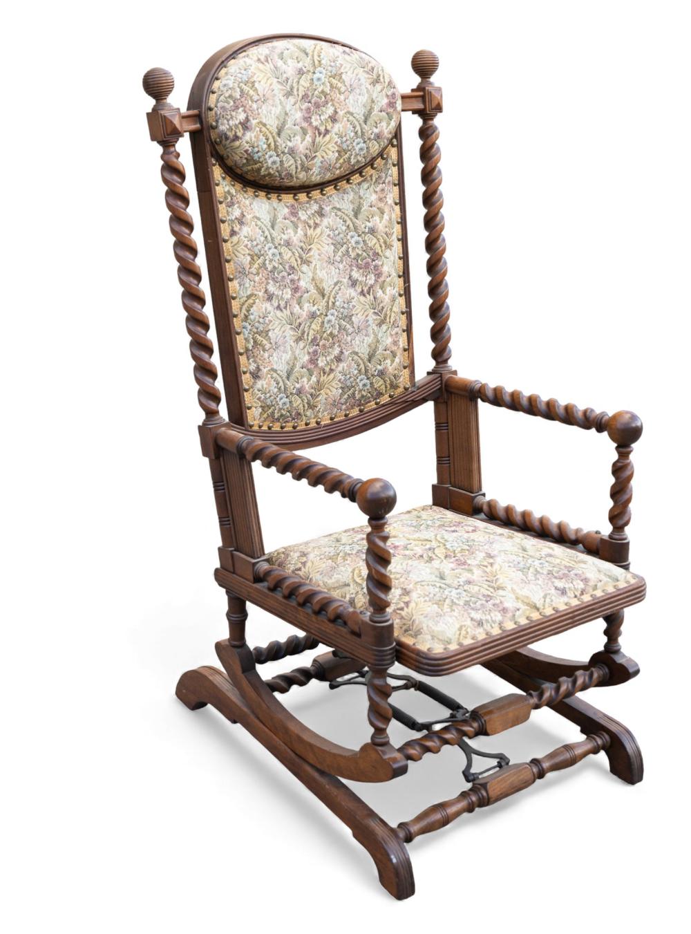 Antique-style wooden rocking chair with spindle turned arms and a floral upholstered seat and back.