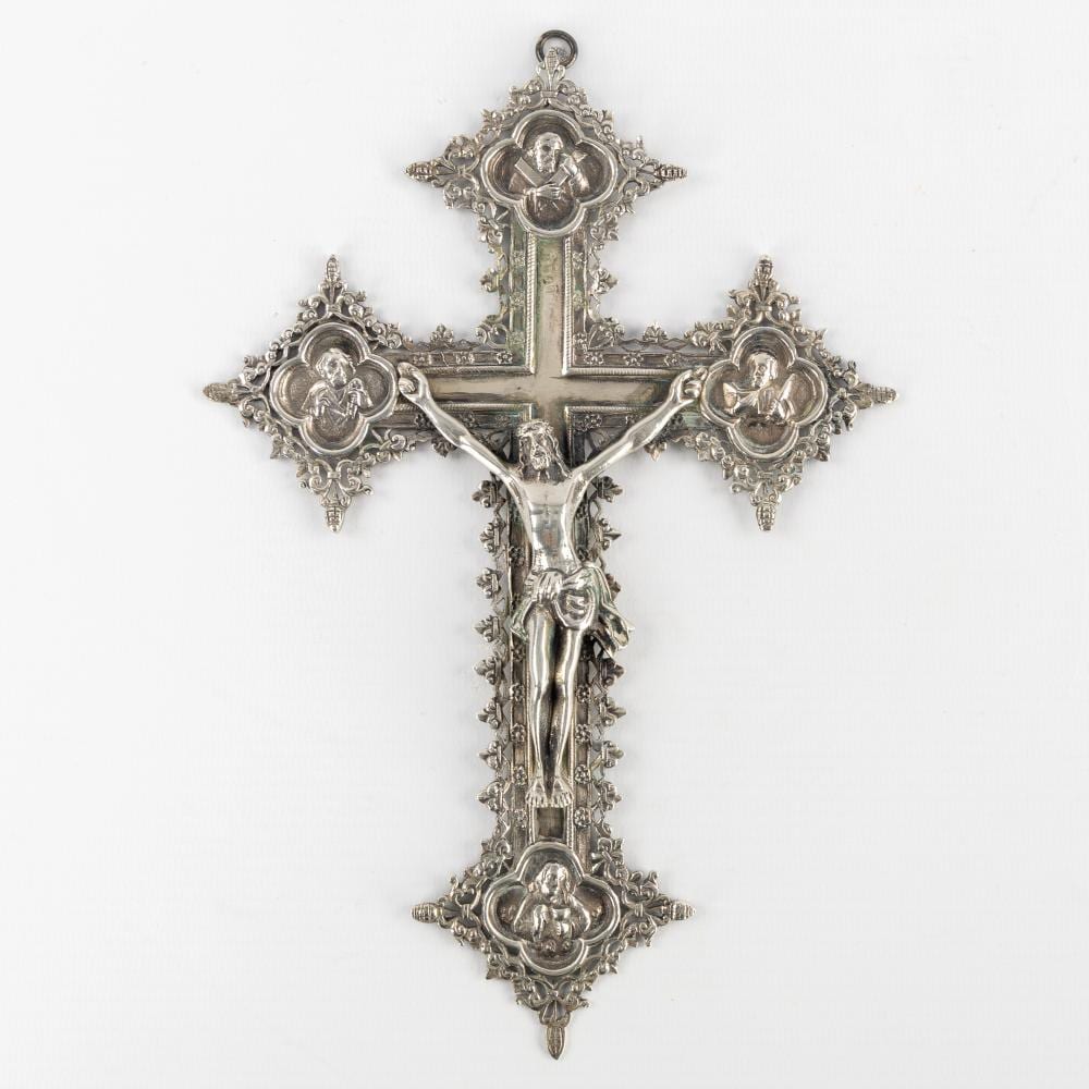 Silver-colored crucifix with a figure of Jesus, ornate filigree scrollwork, and round medallion panels at the ends.