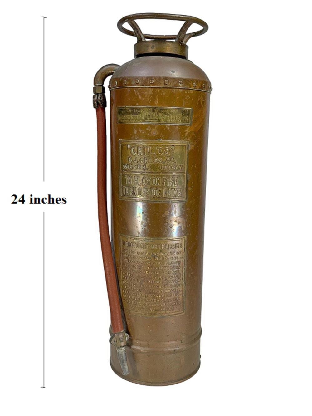 Vintage brass-colored fire extinguisher with top carry handle and side hose, shown against a white background.