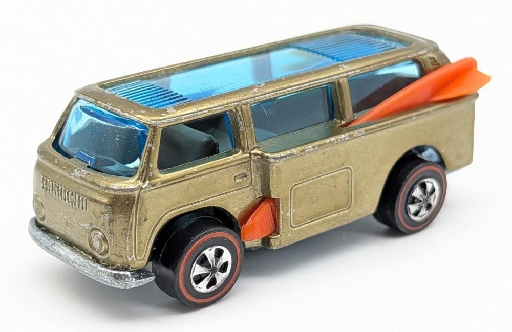 Die-cast toy pickup truck in olive gold with blue windows and an orange surfboard on a white background.