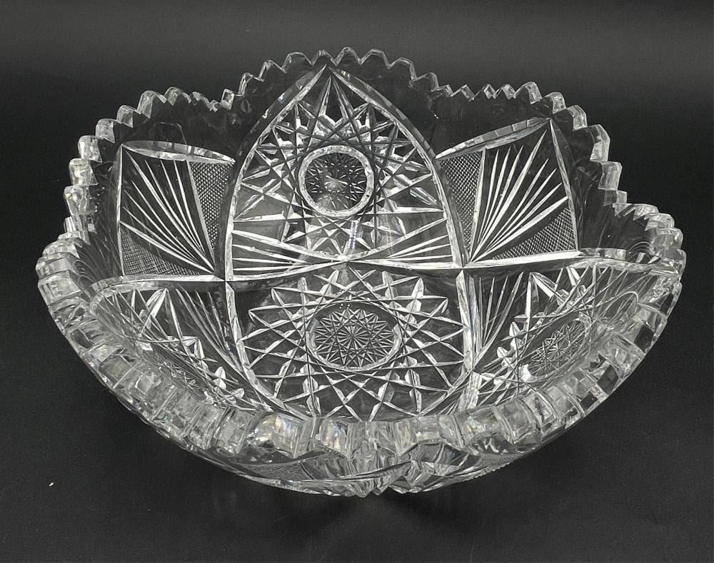 Clear cut-glass bowl with starburst and diamond facets, scalloped rim, and small facets around the sides.