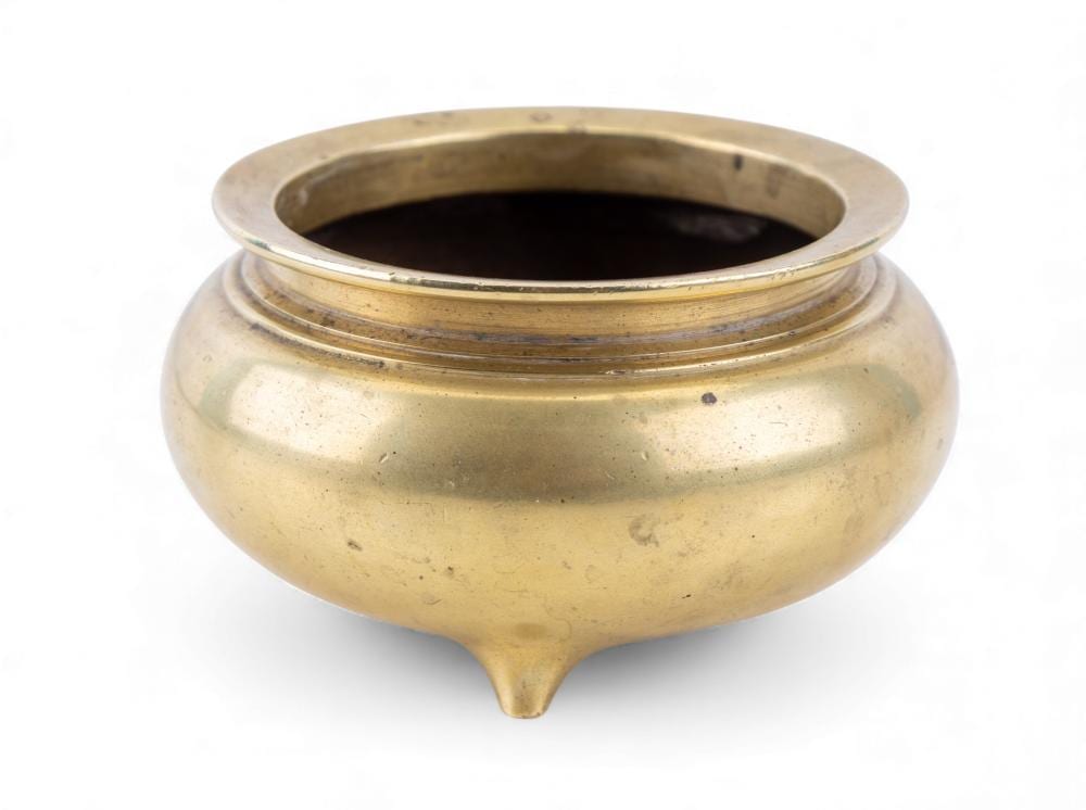 Brass-colored metal incense burner with wide circular opening and three-footed base shape, photographed on a white background.