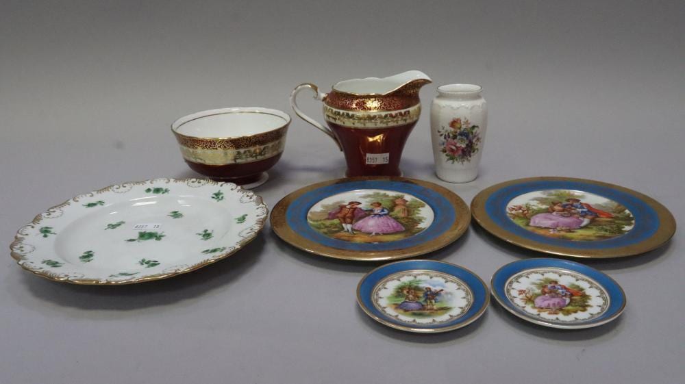 Assorted decorative porcelain ceramics including a gold-brown creamer, a small vase, and several painted plates with floral and figure scenes.