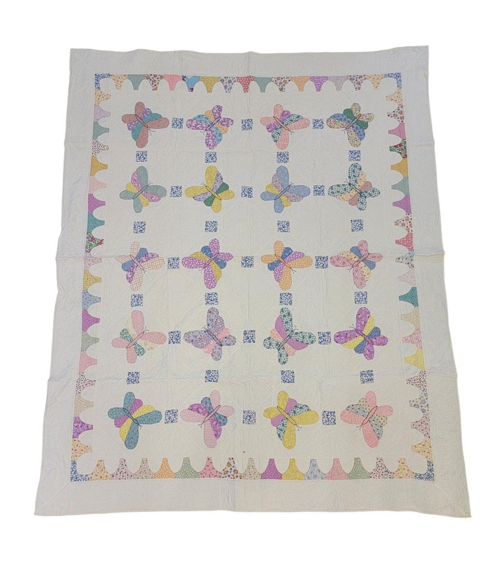 White quilt square with a border of colorful appliqu0 butterfly shapes arranged around a central grid.