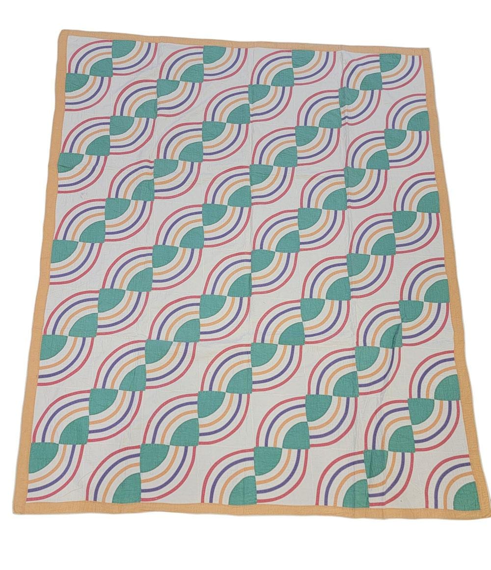 Applique quilt with a checkerboard of square blocks and rainbow arc patterns in teal, green, and multicolor stripes.