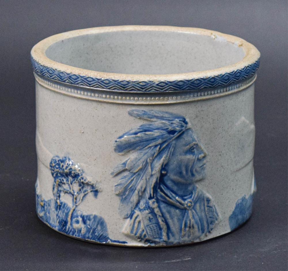 Blue-and-white stoneware crock with a raised rim and painted Native American-style figure decorations on the side.