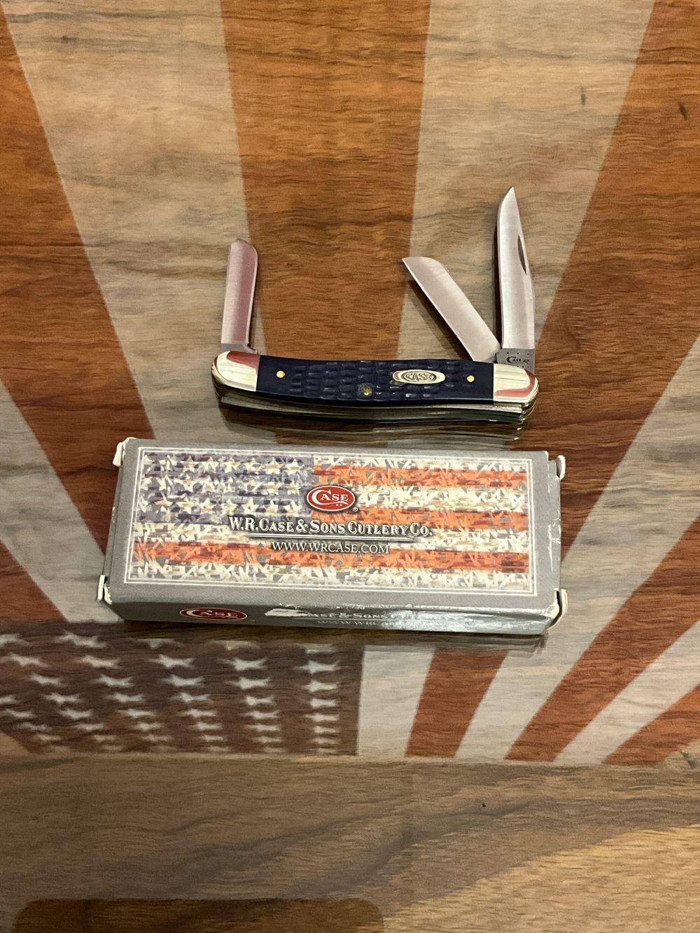 Closed pocket knife on a wooden surface with its blades partially open, beside a branded metal knife case