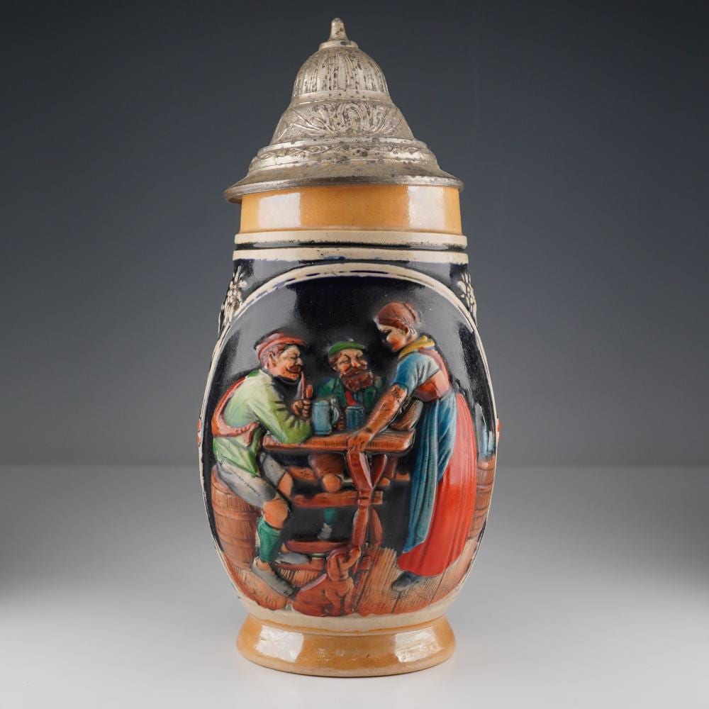 Vintage-style German beer stein with a hinged lid, painted with three men in period clothing holding a tankard and a table scene.