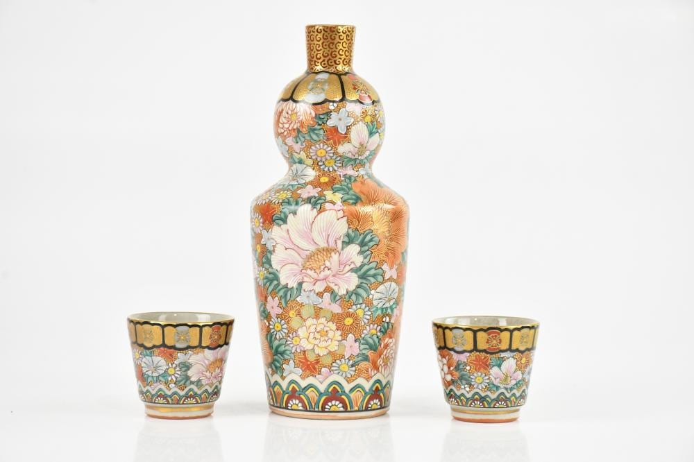 A Japanese Kutani sake bottle and two cups, each with painted floral sprays, with seal mark to the underside, height of bottle 16cm (3). sold by Adam Partridge Auctioneers, lot 1440 — auction record photograph