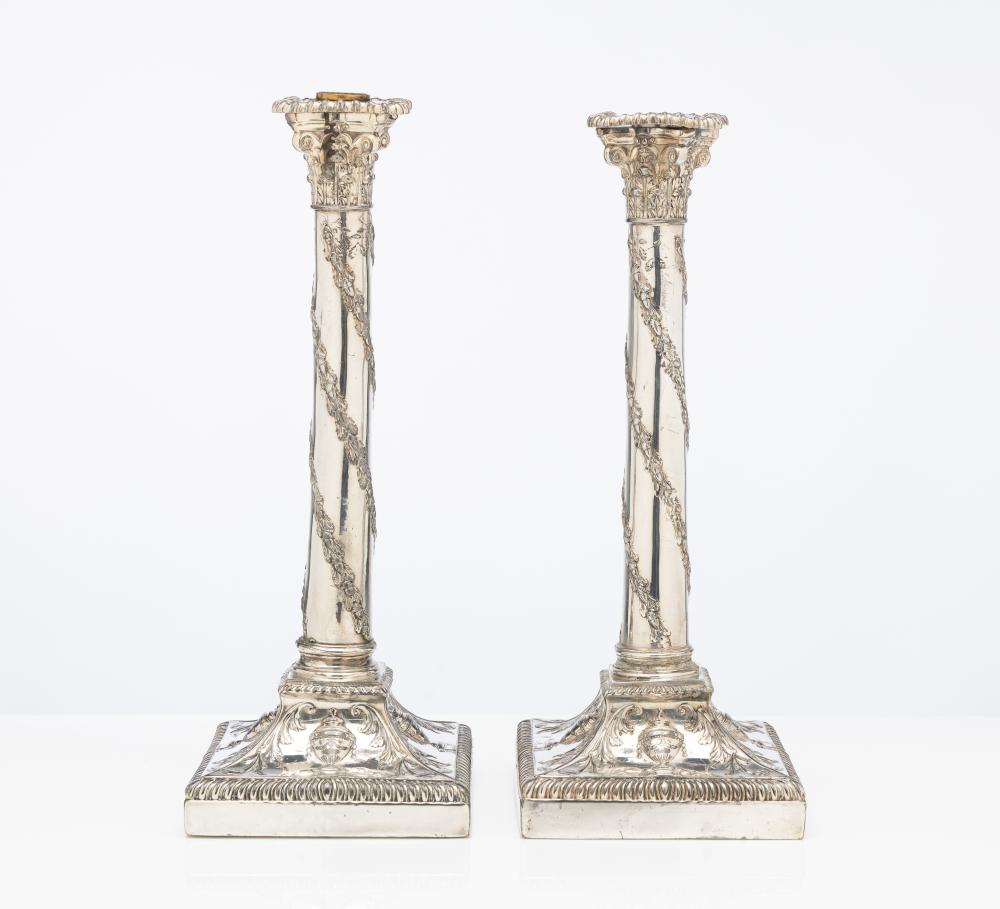 Pair of tall silver-tone candlesticks with ornate column bodies and square bases, shown side by side against a white background.