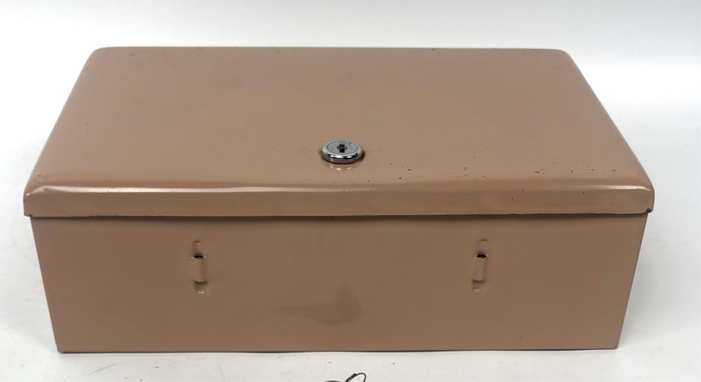 Rectangular tan metal locking cash box with a circular key lock on top and two small latch/handle cutouts on the front.