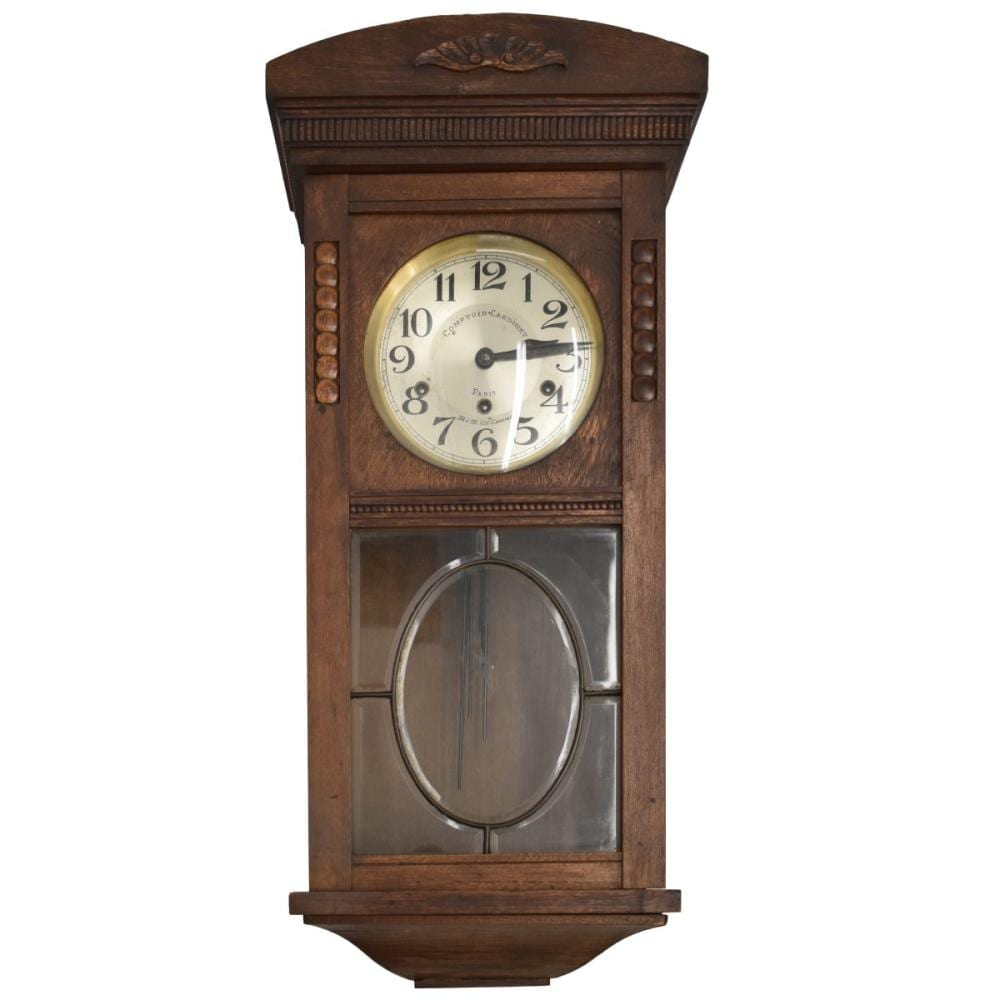 Front view of a wooden wall clock with a round white dial and black numbers behind glass, with an arched top and pendulum window below.