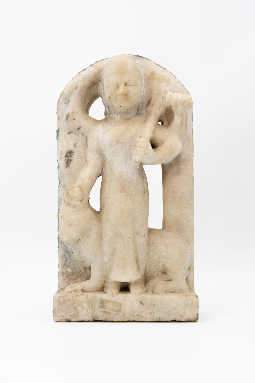 Stone carving sculpture of a multi-armed seated figure holding a round object, shown against a white background.