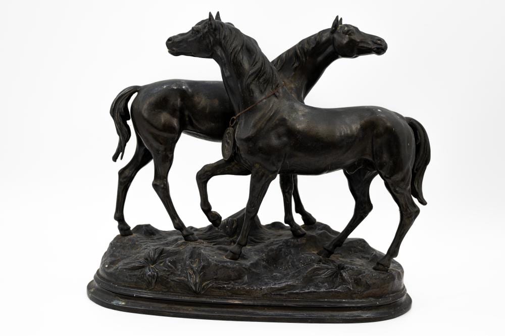 Bronze-colored sculpture of two standing horses rearing and standing, posed on a dark oval base.