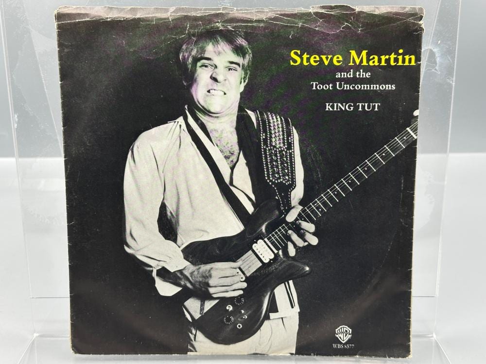 Vinyl 45 RPM record picture sleeve showing Steve Martin holding an electric guitar, with yellow “Steve Martin” text and song titles “King Tut” and “Toot Uncomm…