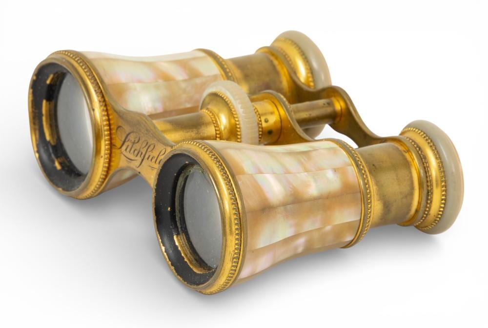Antique-style opera glasses with pearly mother-of-pearl look barrels and gold-toned rims, shown open in a photo on a white background.