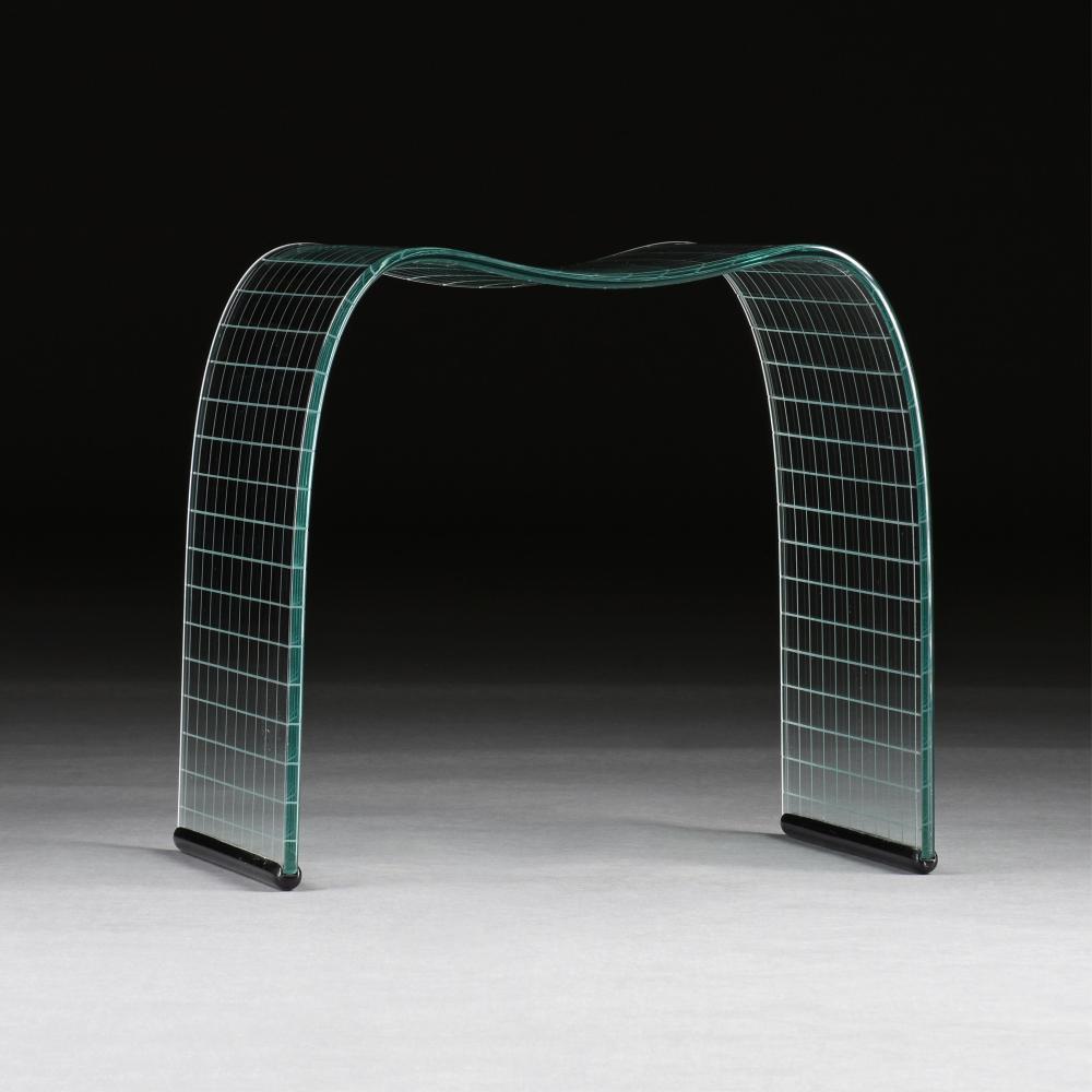 Transparent arched glass sculpture with a curved, gridded form on dark supports.
