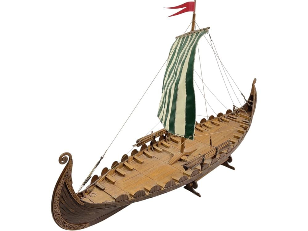 Wooden Viking longship model with a green-and-white striped sail, rigging ropes, and a carved dragon-style prow.