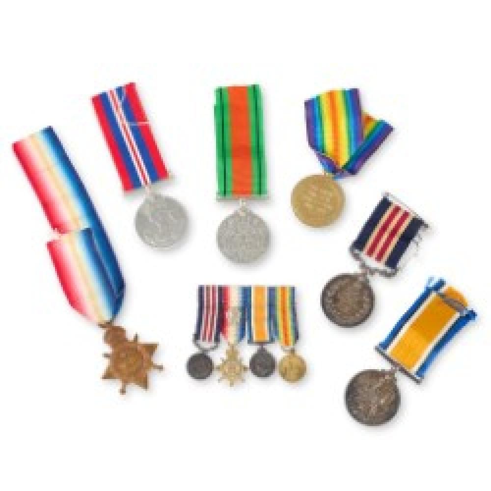 Group of military medals with colorful ribbon bars and several round medal discs arranged on a white background.