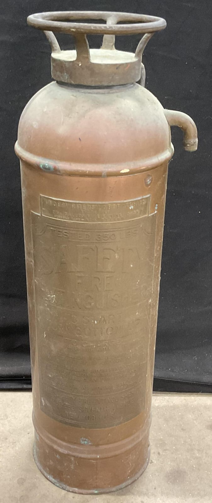Antique-style copper fire extinguisher with rounded body, top handle nozzle, and embossed label details.