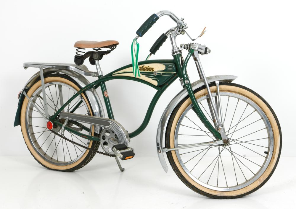 Green and cream vintage-style children’s bicycle with a brown saddle, chrome fork, and front wheel turned slightly right.
