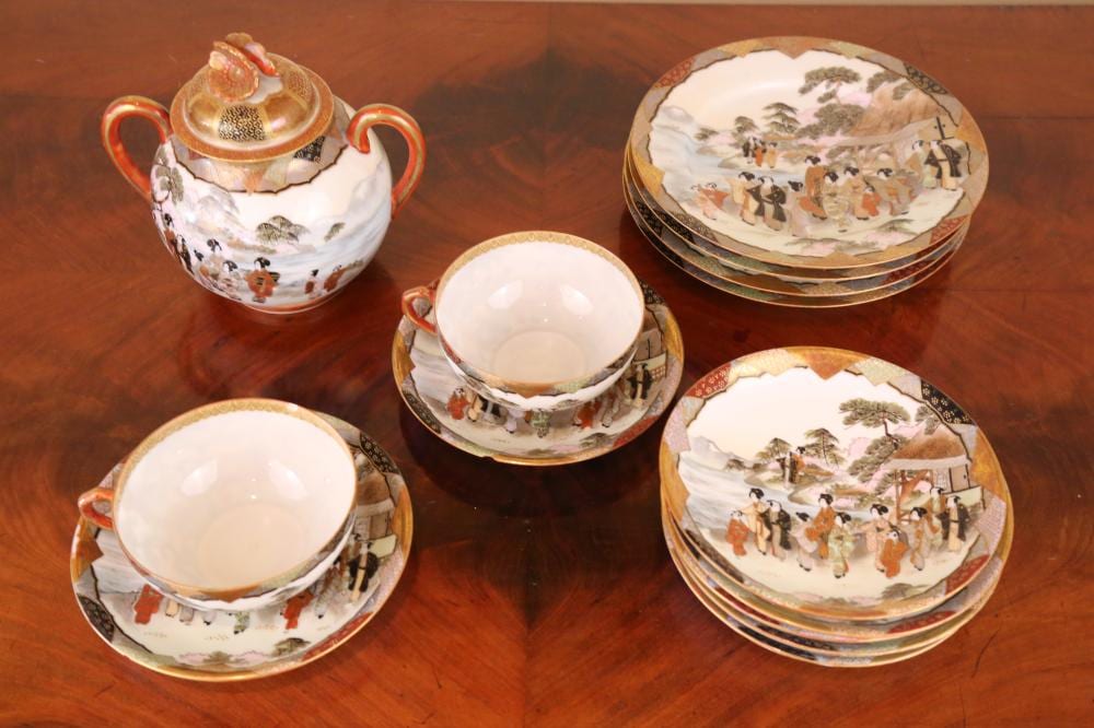Porcelain Japanese-style tea set with teapot and four cups and saucers, painted with village and people scenes.