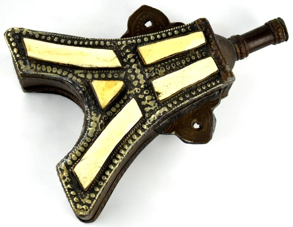 Decorative metal powder flask in the shape of a hand gun, with brass-colored inlay and studs on a dark body and a cylindrical spout.