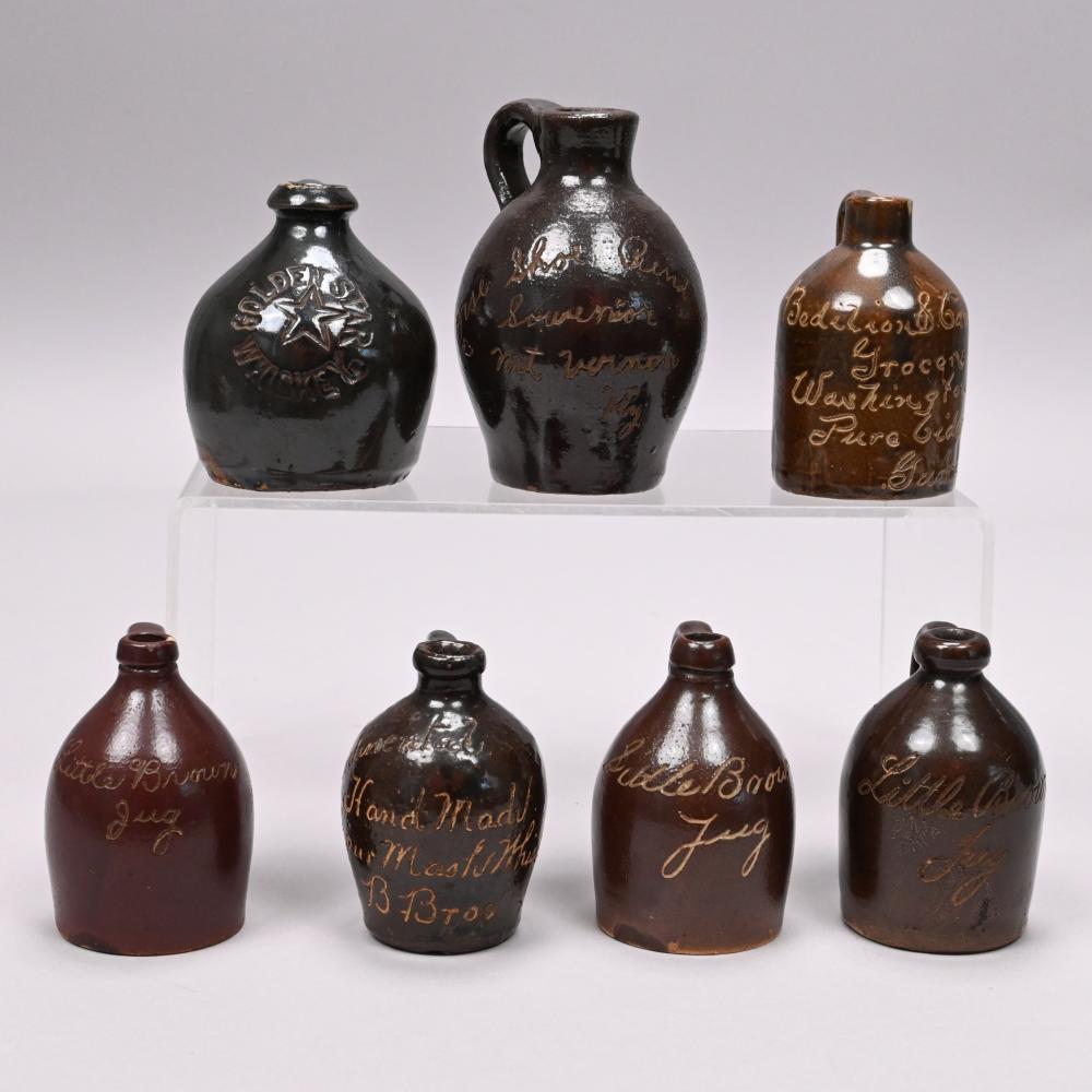Seven Stoneware Souvenir and Advertising Jugs sold by Devin Moisan Auctioneers, Inc., lot 842 — auction record photograph