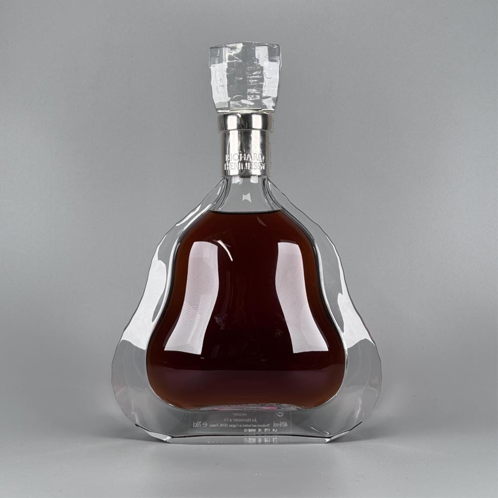 Glass cognac decanter with faceted stopper, showing a dark amber liquid and a label reading “RICHARD HENNESSY.”
