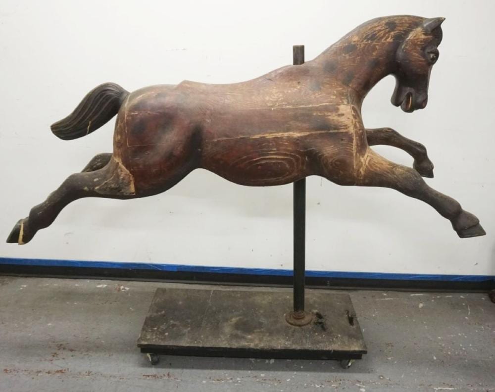 Carved wooden carousel horse figure with dark brown finish, mounted on a metal stand against a white background.