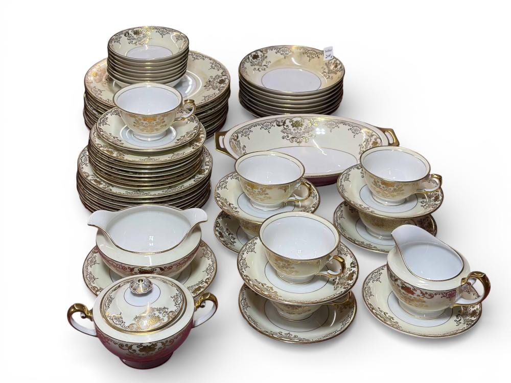 Mixed set of decorative china dinnerware with matching saucers, cups, plates, and a serving bowl; gold and patterned borders on white porcelain.